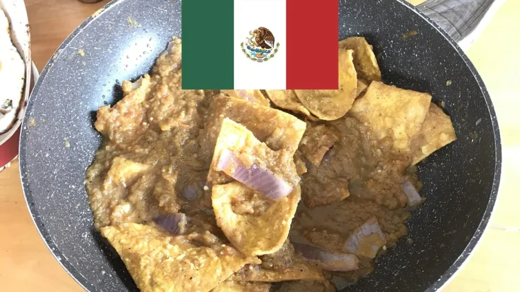 Chilaquiles caseros en una sartén junto a una bandera de México.