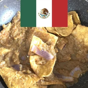 Chilaquiles caseros en una sartén junto a una bandera de México.