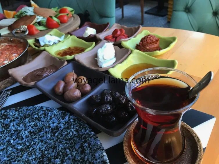 Desayuno turco servido con té, aceitunas, quesos y verduras.