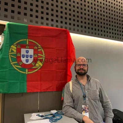 Hombre sentado junto a una bandera de Portugal en un recinto interior.